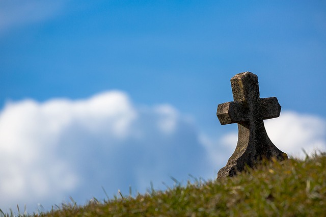 picture of gravestone (in the form of a cross) on a hill