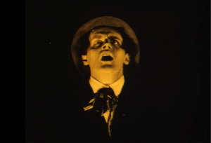 A screen shot from the film of Alan's face showing fear, with darkness all around it